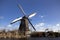 Old, traditional windmill in the Dutch canals. Netherlands.White clouds on a blue sky, the wind is blowing.