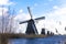 Old, traditional windmill in the Dutch canals. Netherlands.White clouds on a blue sky, the wind is blowing.