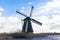 Old, traditional windmill in the Dutch canals. Netherlands.White clouds on a blue sky, the wind is blowing.