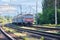 An old train rushes along the railway leaving the city on a summer sunny day