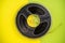 Old transparent plastic reel with audio or video tape on yellow background with copy space. Bobbin, retro magnetic spool