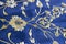 Old Turkish embroidered fabric with golden geometric and floral decorations against a blue background