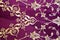 Old Turkish embroidered fabric with golden geometric and floral decorations against a purple background