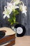 Old turntable. Several vinyl records and blossoming lilies against a background of black and white pine boards