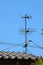 Old TV antenna on house roof with blue sky.