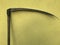 An old two-handed scythe for hay. It stands against a wall covered with stucco. The wall is painted yellow