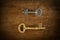 Old two keys placed on a wooden floor loe key light.