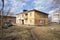 An old two-storey one-entrance residential building, built in the time of Stalin, stands in a microdistrict on a sunny spring day