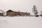 Old two-storied red house in winter with snow, cars and trees on the yard. Poverty and misery, North