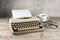 Old typewriter from the 1950s with blank paper, coffee and glasses on rustic wood, pale vintage color style, copy space