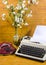 Old typewriter, telephone and ancient vase with camomiles