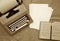 Old typing machine, white sheets of paper,old book on an old paper surface.