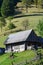 The old Ukrainian hut with a slate roof and a wooden fence in a green fiel