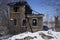 An old unkept abandonned traditonal russian wooden two floor house in ruins in winter snow surrounded by naked birch trees and