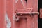 An old unlocked sliding bolt door and gate latch on peeling painted corrugated iron door