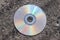 Old used compact disc on an asphalt road. Close up view