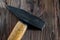 Old used hammer with wooden handle, metal head on rustic dark wooden backdrop