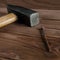 Old used hammer, wooden handle, metal head and rusty nail on wooden backdrop