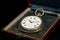 Old used pocket watch in a case on a black reflective surface
