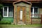 Old village wooden house front yard entrance with brown door and grass