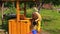 Old villager woman at well, draw water and pour it to bucket