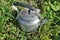 Old vintage aluminum electric kettle on a green rustic lawn