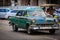 old vintage classic taxi car driving on Cuban Havana city street with people in background