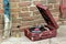 Old vintage gramophone player in a red case abandoned outside