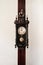 Old vintage grandfather wooden wall clock hanging on wood pillar