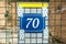 Old vintage house address blue metal number 70 seventy on the gate and mail or letter box of residential building exterior wall on