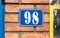 Old vintage house address blue metal number 98 on the gate and mail or letter box of residential building exterior wall on