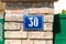 Old vintage house address metal number 30 thirty on the brick facade of abandoned home exterior wall on the street side