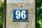 Old vintage house address metal plate number 96 ninety six on the plaster facade of abandoned home exterior wall on the street s