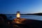 An old vintage oil lantern on a rock by the sea. Evening time.