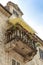 Old, vintage, ornate balcony with a modern yellow canopy in Kotor, Montenegro