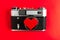 Old vintage photo camera with red heart on it. red background.for decor and design. valentines greeting card.