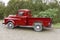 Old vintage red pickup truck carrying a Christmas tree in the be