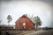 Old vintage red wood barn in country with metal corral and truck approching on two lane blacktop hgihway