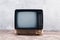 Old vintage retro analog TV set stand on wooden floor front aged concrete wall background