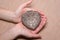 Old vintage silver heart-shaped casket in female hands on light coloured background.