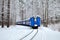 An old vintage train with beautiful blue Passenger cars rides by rail through a winter snowy forest.