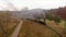 Old vintage train locomotive moving through the breathtaking forest railway, mountains landscape, autumn colors, drone shot