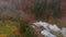 Old vintage train locomotive moving through the breathtaking forest valley in mountains, autumn colors, drone shot