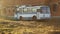 Old vintage white blue soviet union ussr relic bus in sunny summer day in field in front of yellow orange brick wall