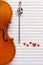Old violin, pencil treble clef shape and red heart figurines. Top view, close up, flat lay on white music paper background