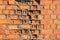 An old wall of collapsed, cracked, crumbling red brick.