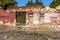 Old wall of destroyed house. Old powder wall with walled window and gates, doors. Ruined house. Remains of old houses. Apocalypse