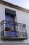 Old wall with peeling paint, scratched vintage plaster and a balcony with a blue door and blinds with wrought iron bars.