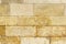 An old wall piled of stone yellow blocks. Natural background for design or texture