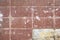 Old wall of rectangular red tiles with stains of paint and dirt and broken tile. rough surface texture